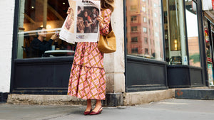 Woman reading a newspaper outside a 'Variety Coffee Roasters' store.
