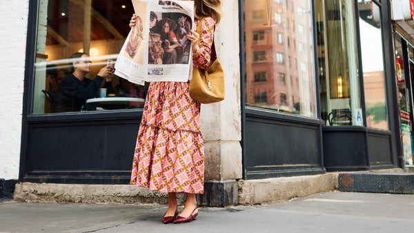 Woman reading a newspaper outside a 'Variety Coffee Roasters' store.